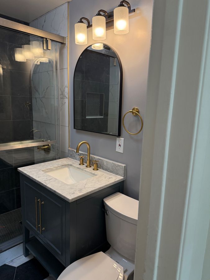 Bathroom vanity with Carrara marble countertop and brass fixtures