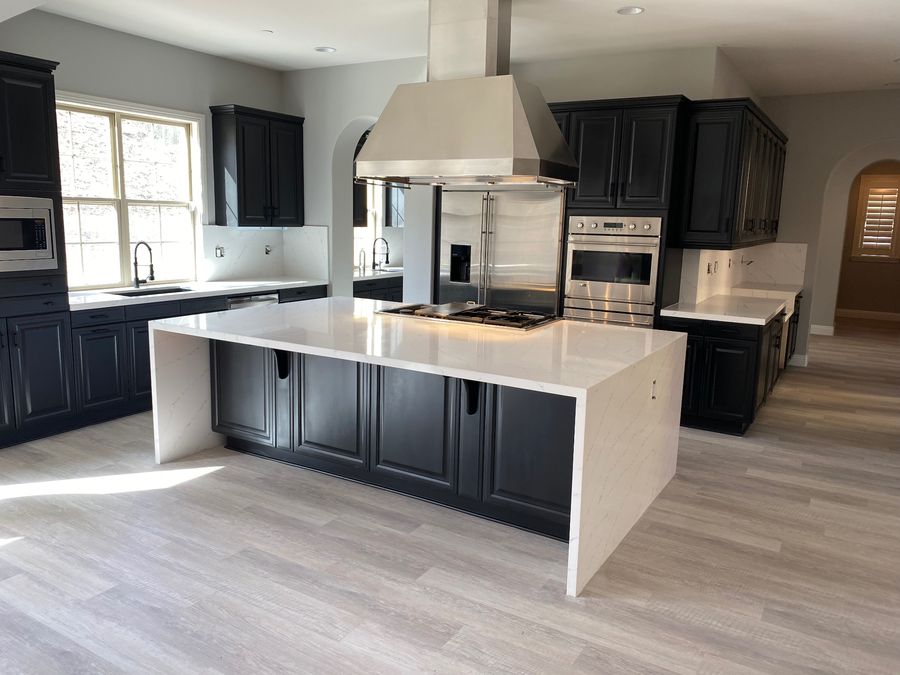 Modern kitchen with white quartz waterfall island and black cabinetry